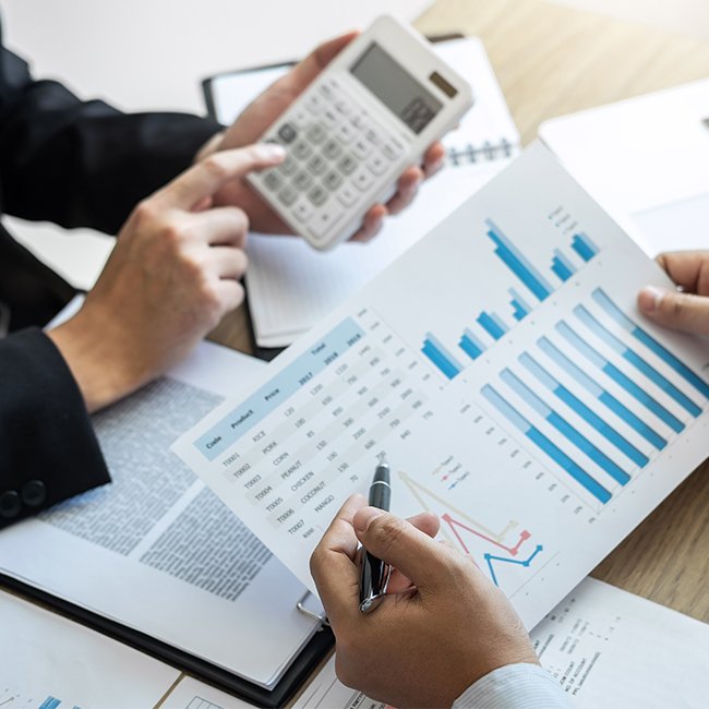 Two people reviewing financial graphs and using calculator for accounting services