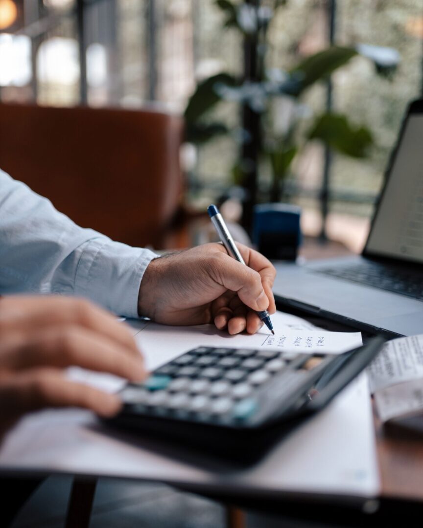 Person using calculator and writing at desk for tax planning services